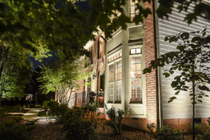 side view of apartment building with inground lighting and beautiful trees in front of window