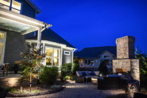 backyard with fire place and inground lighting around patio with cobblestone walkway