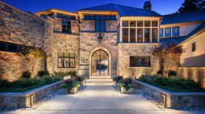 beautiful view of front of stone home large walkway with inground lighting beside plant boxes